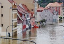 Prueban que la crisis climática provoca inundaciones más graves Calle inundada con el agua cubriendo puertas y ventanas