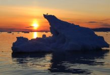 Extrema reducción del hielo Ártico en octubre Trozo de hielo ártico derritiéndose con el sol al fondo