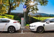 Promover el coche eléctrico no funcionará sin un cambio de modelo urbano y movilidad Dos coches eléctricos cargándose frente a un paisaje campestre