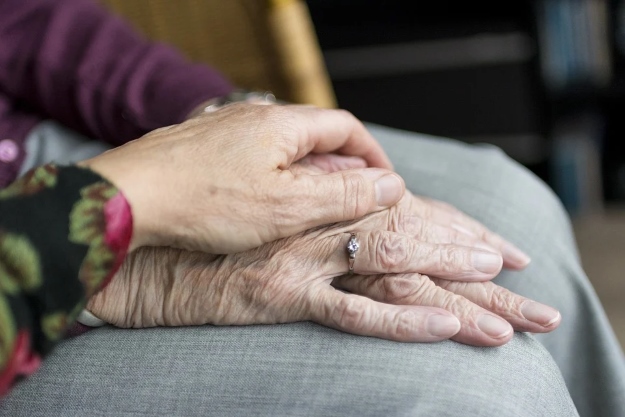 Mujer acaricia mano de anciana